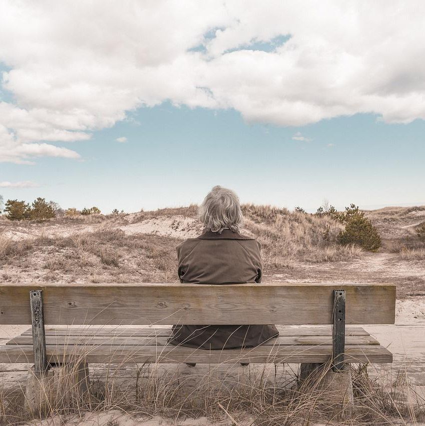 Person sitter på benk og ser ut over landskap