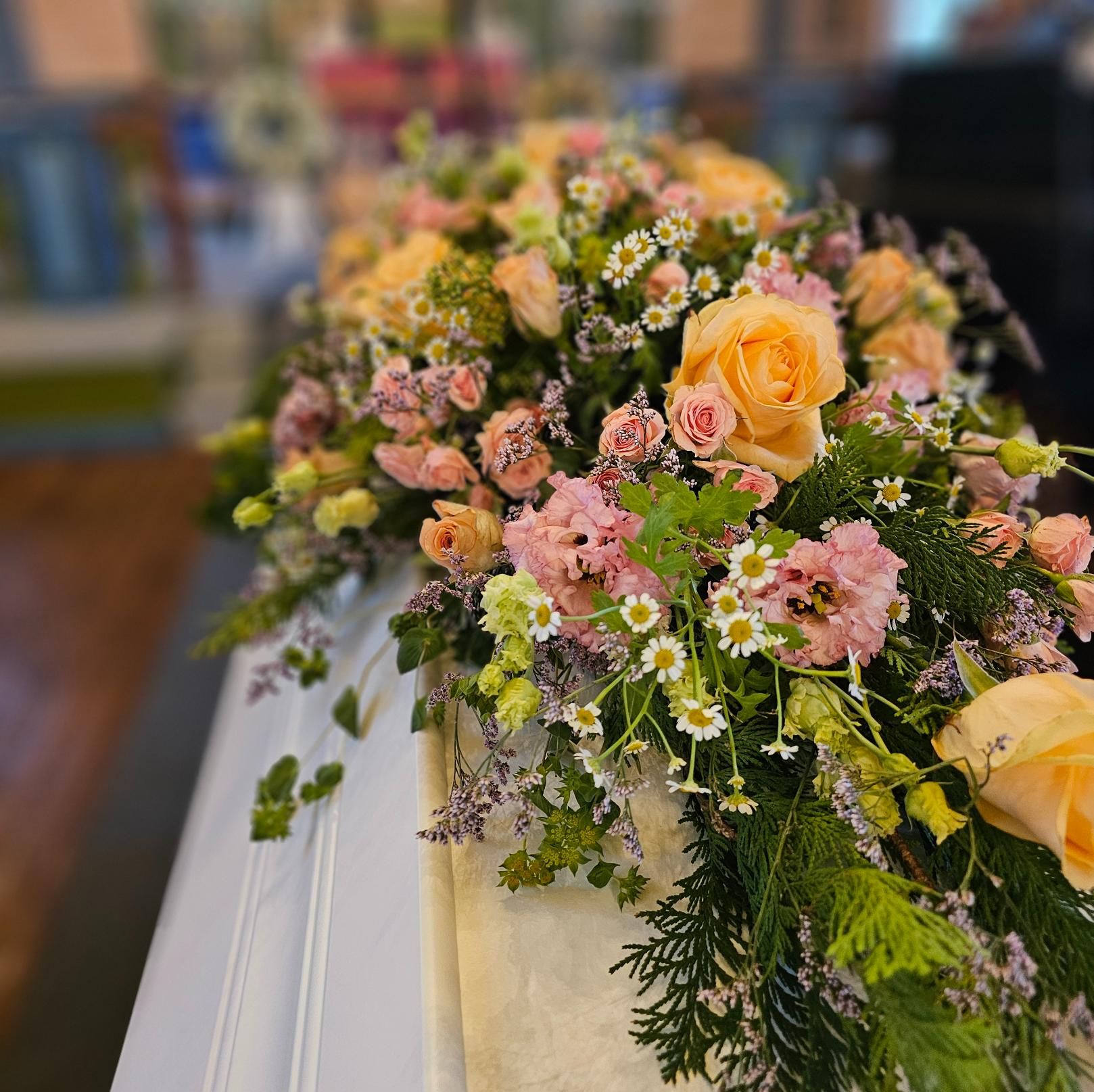 Blomsterbuketter på hvit kiste